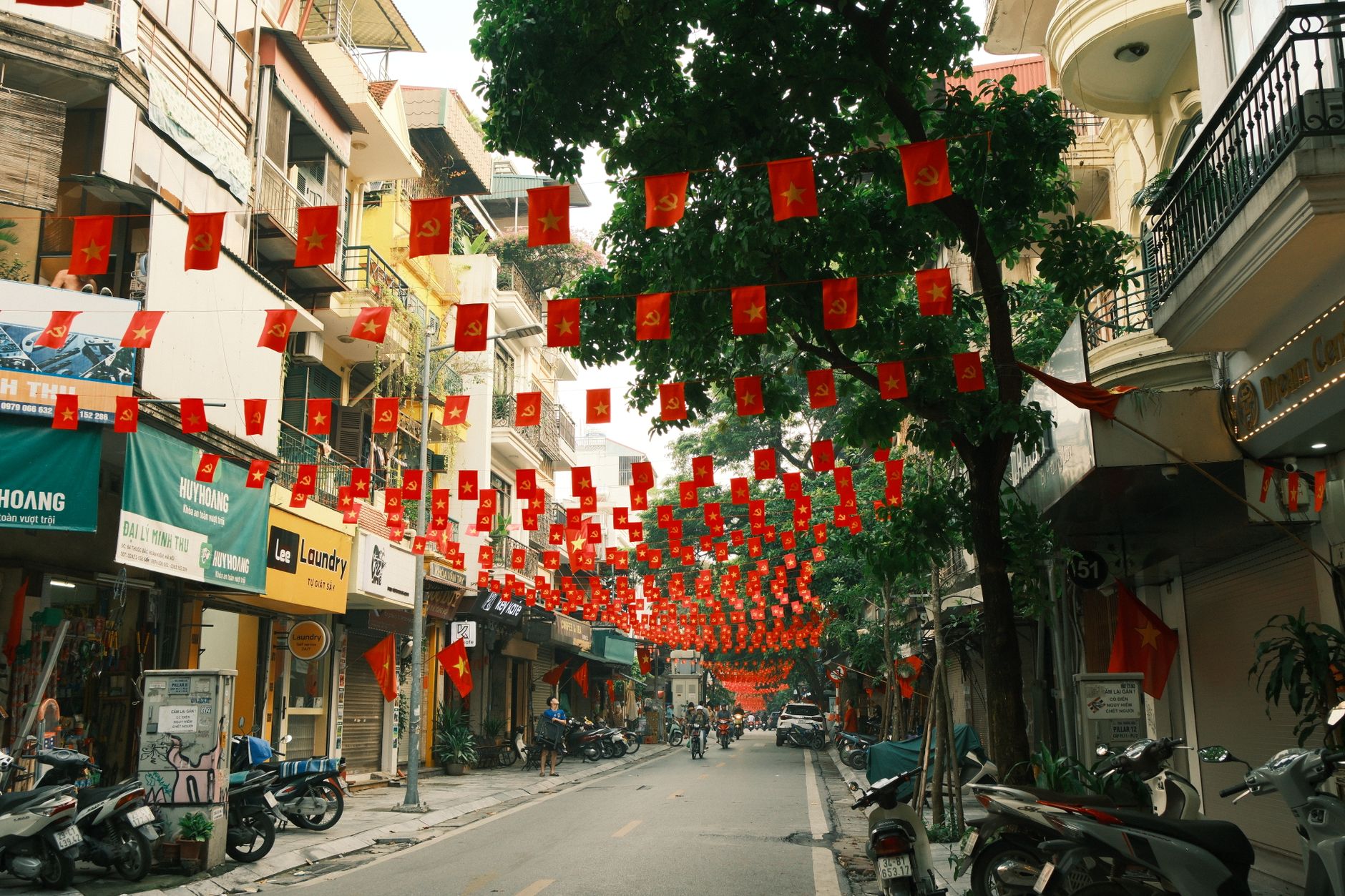 Vibrant Hanoi street festooned with Vietnamese flags and bustling local life.