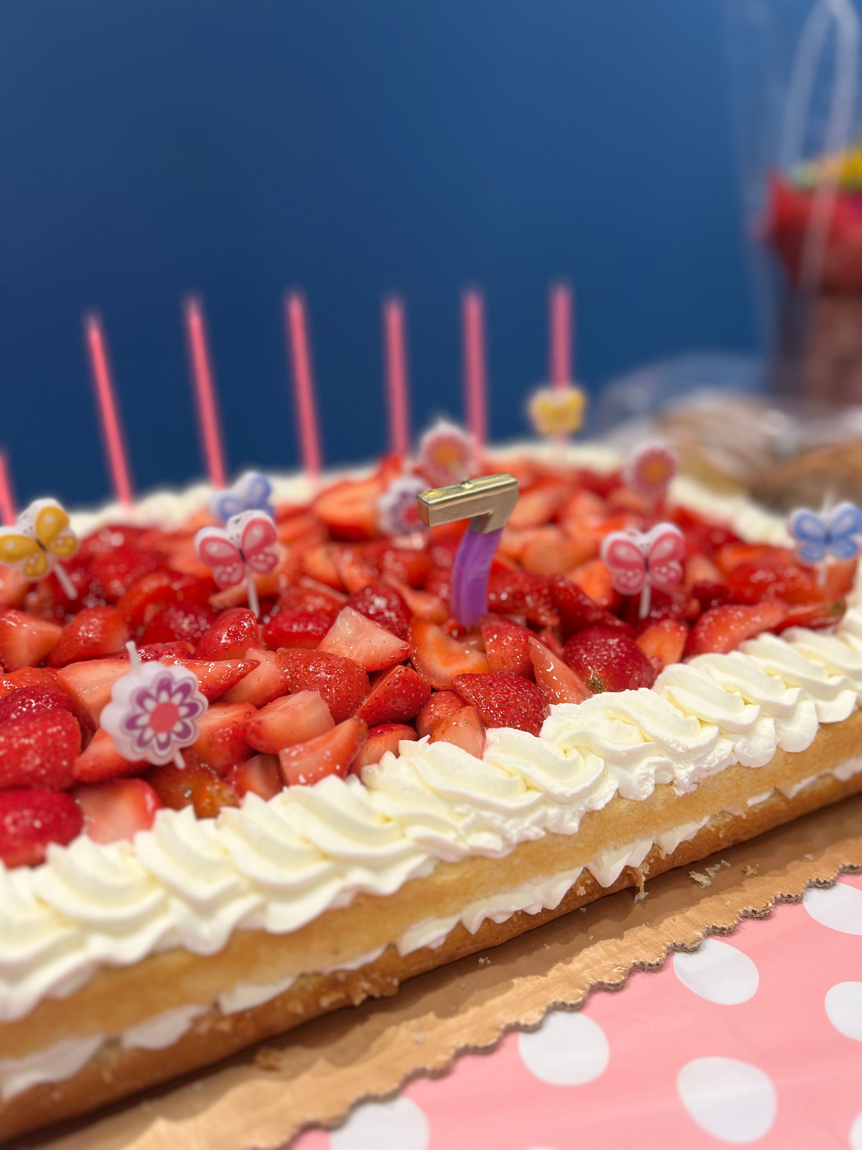 Festive strawberry cake with candles and number seven decoration, perfect for birthday celebrations.