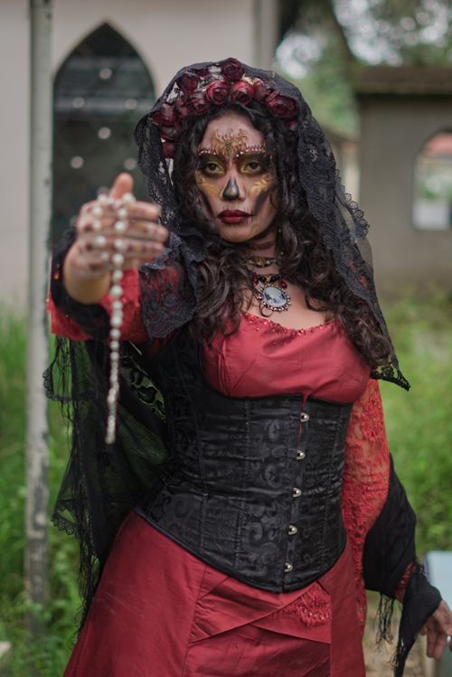 Free A striking portrait of a woman in a Day of the Dead inspired costume outdoors. Stock Photo
