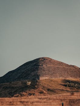 在日落时，晴朗的天空下宁静的山丘捕捉到了大自然的美丽