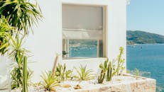 明亮的海岸景观，以石头仙人掌花园为特色，可以俯瞰大海，船上有船只