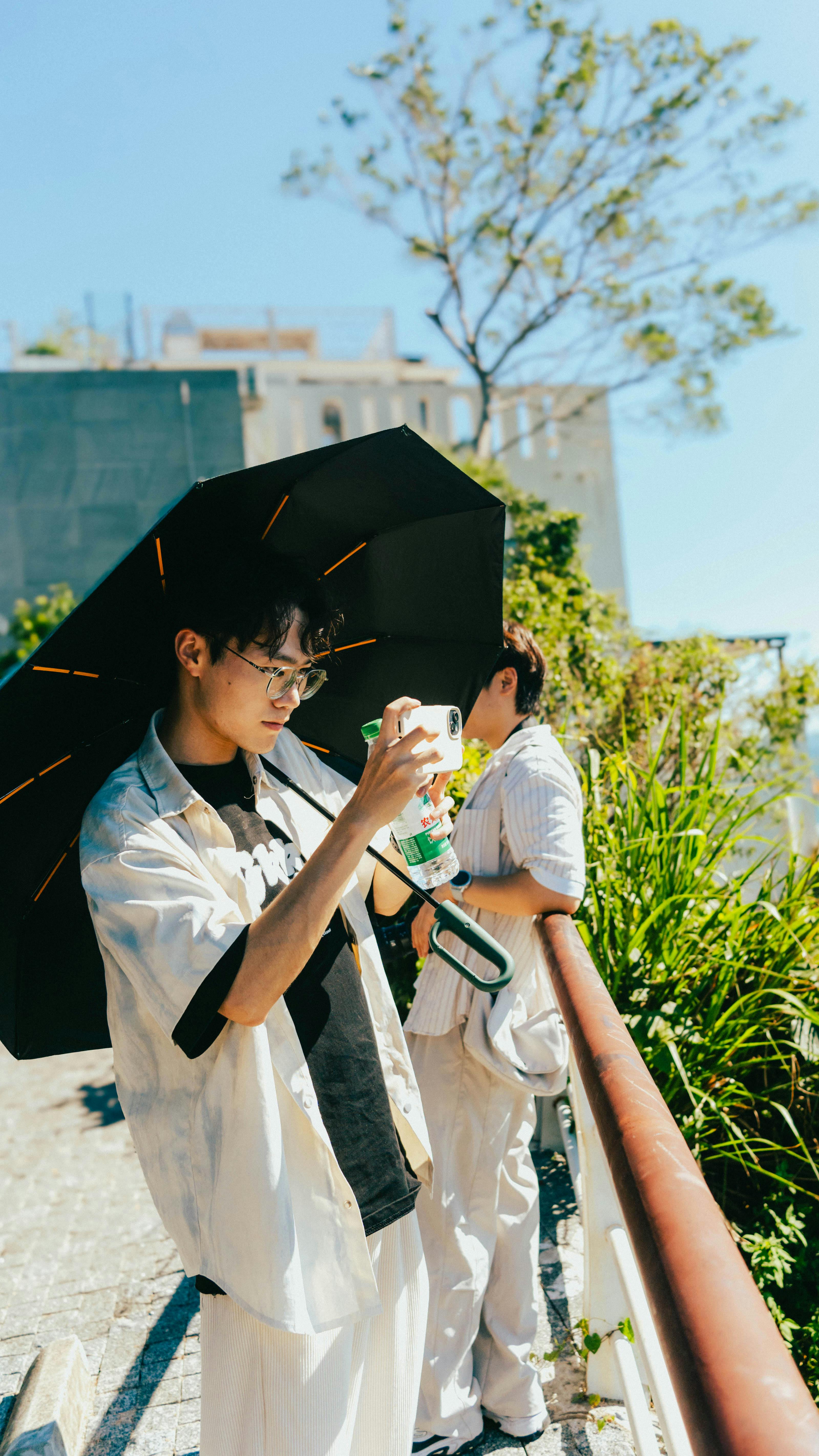 两个年轻人站在绿树环绕的阳光露台上，享受着这美好的一天