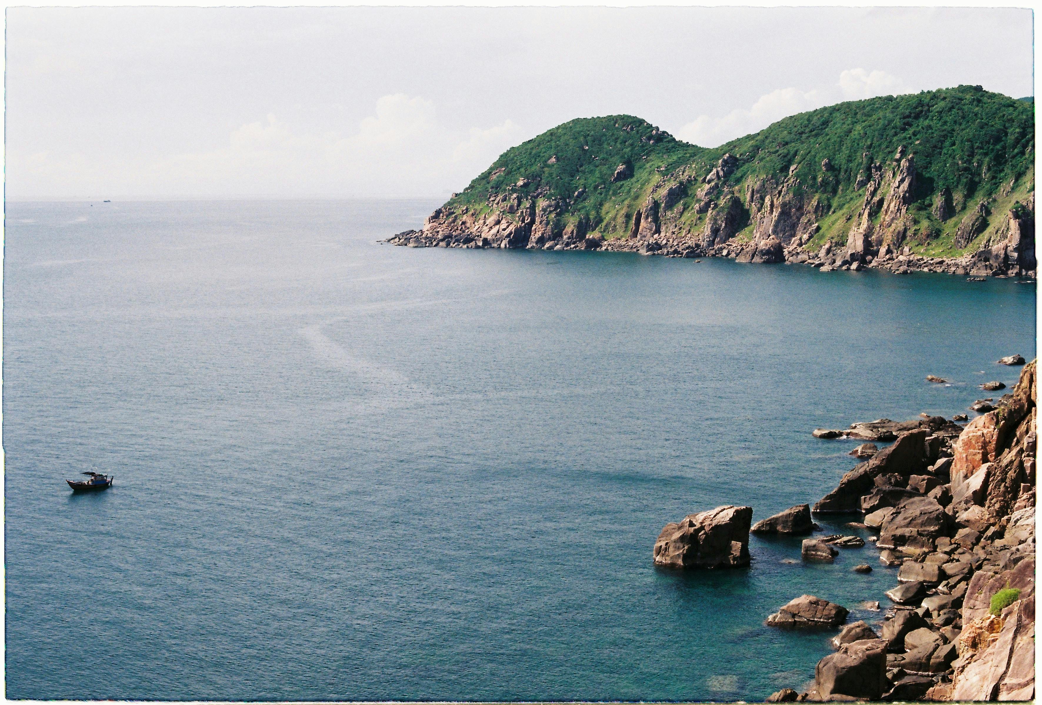 宁静的沿海场景，以岩石悬崖和晴朗的天空下远处的船只为特色