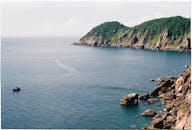 宁静的沿海场景，以岩石悬崖和晴朗的天空下远处的船只为特色