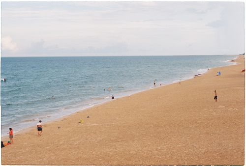 Free A tranquil beach scene with people enjoying the sunny day by the sea. Stock Photo