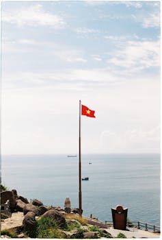 越南国旗在晴朗的天空下飘扬，沿海景观美丽