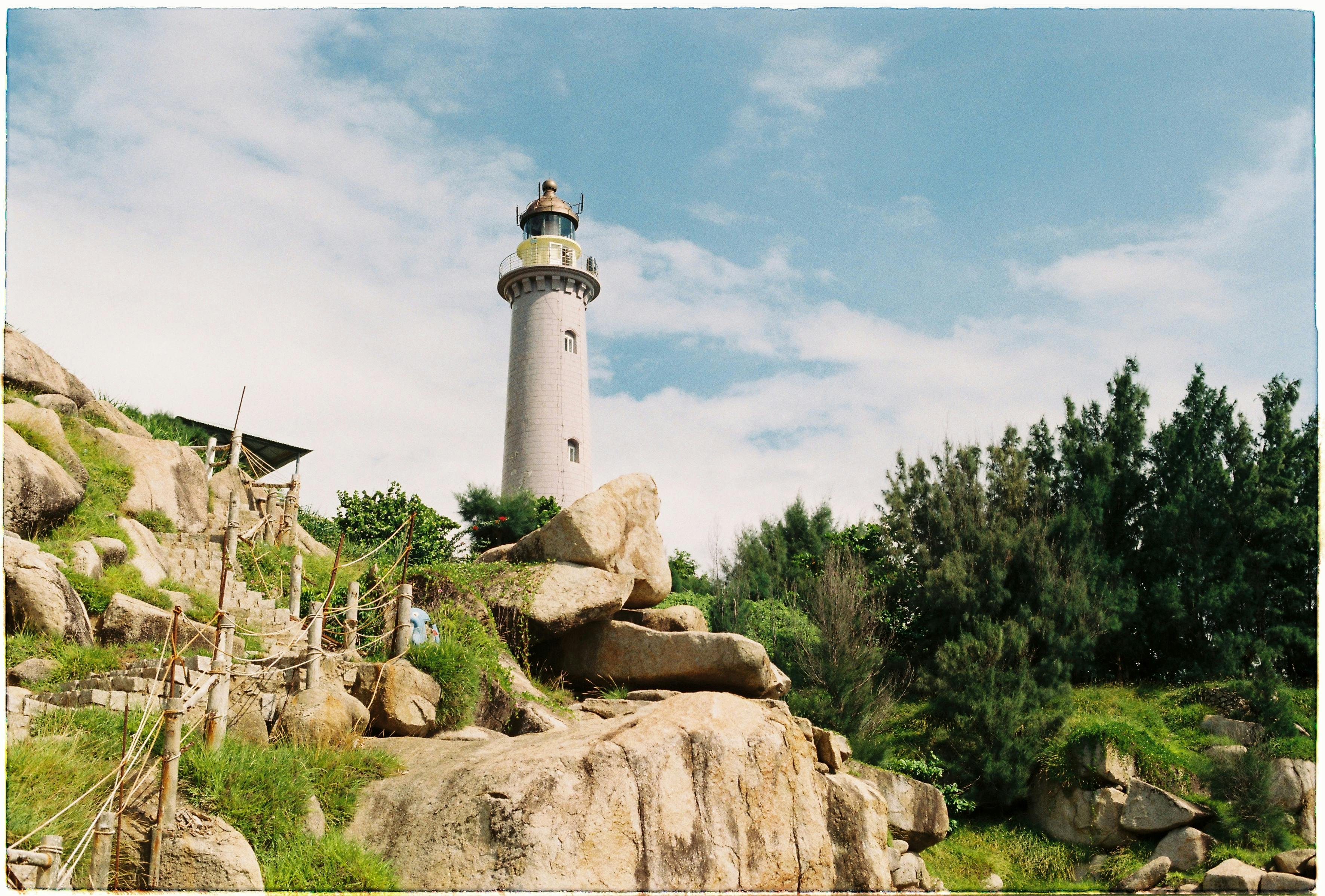 在湛蓝的天空下，一座风景如画的灯塔高耸地矗立在岩石峭壁之上