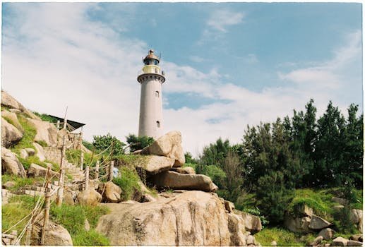 在湛蓝的天空下，一座风景如画的灯塔高耸地矗立在岩石峭壁之上