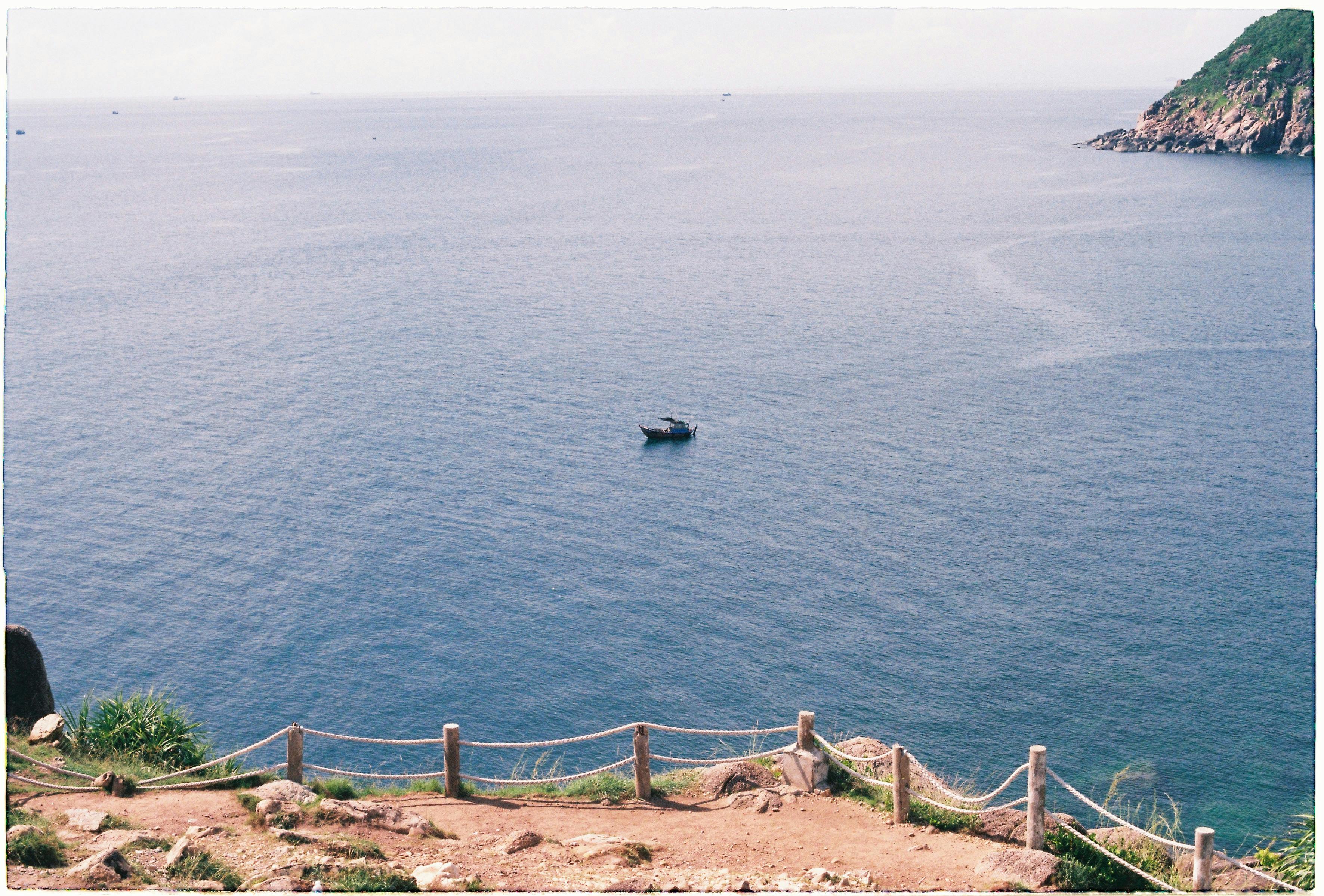 在晴朗的天空下，宁静的海洋上漂浮着一艘孤独的船