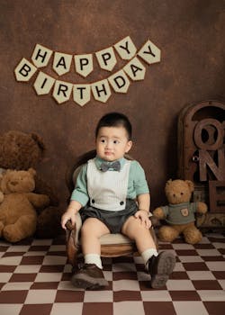 Adorable baby in formal attire celebrating first birthday with teddy bears.