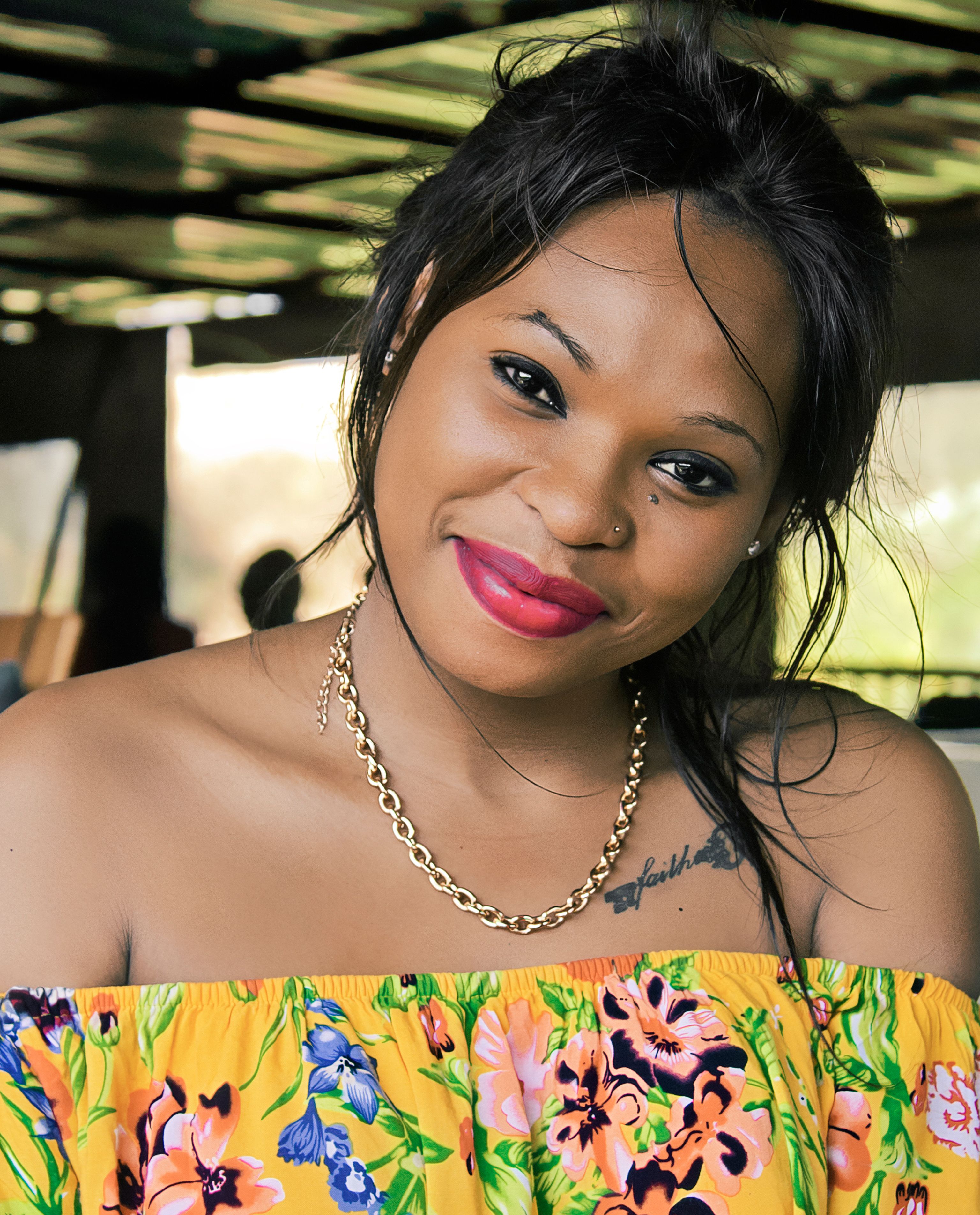 Smiling woman wearing a colorful floral dress and gold chain in Eswatini.