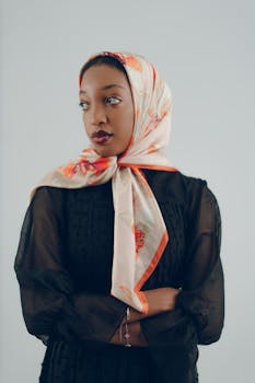 一位优雅的女士，头戴花卉图案的头巾，身着黑色薄纱连衣裙，自信地看向一旁