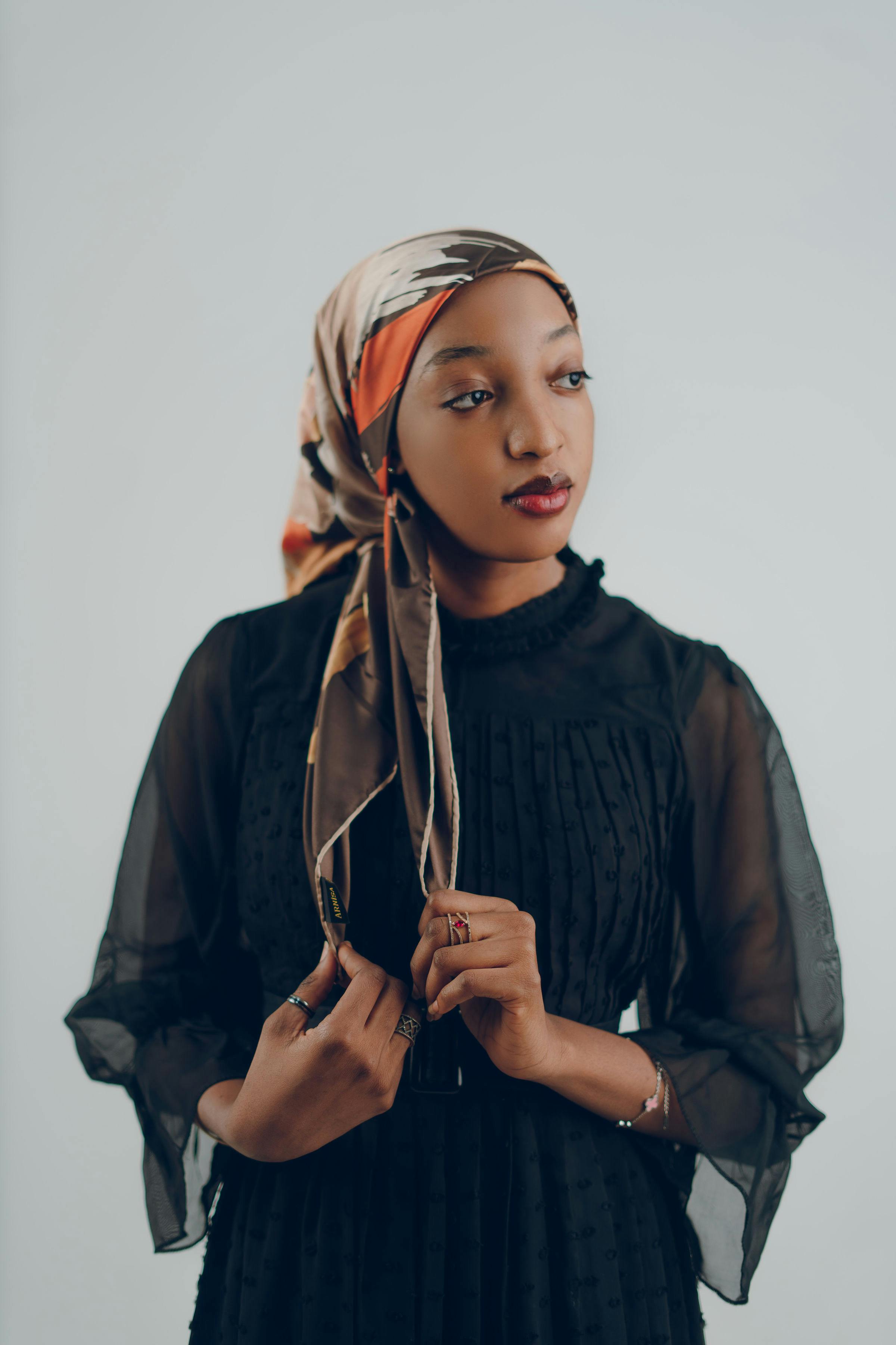 一位身穿黑色连衣裙、戴头巾的女性优雅地摆姿势的肖像