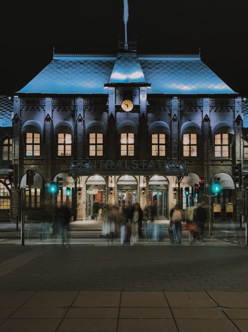 Free Nighttime view of Gothenburg Central Station with blurred pedestrians and illuminated facade. Stock Photo