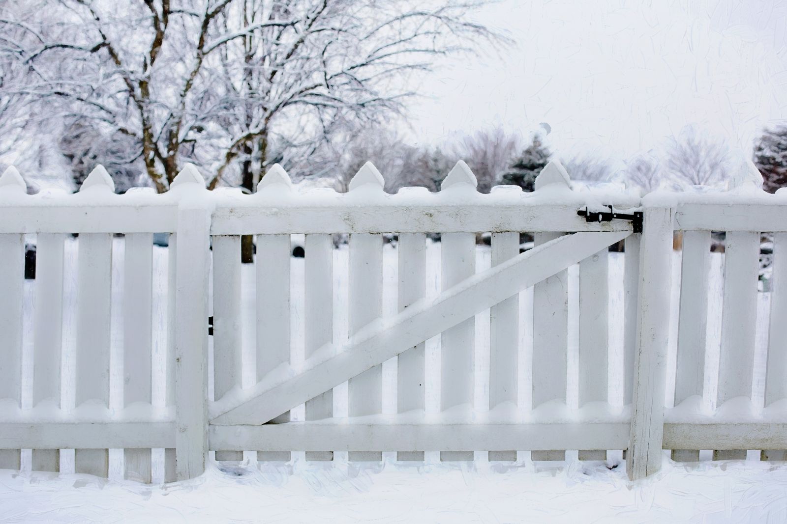 White picket fence standing in winter snow