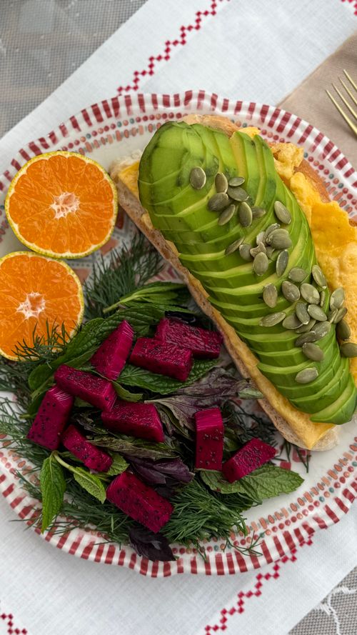 Free Colorful breakfast plate featuring avocado toast, fresh citrus, and vibrant salad greens. Stock Photo