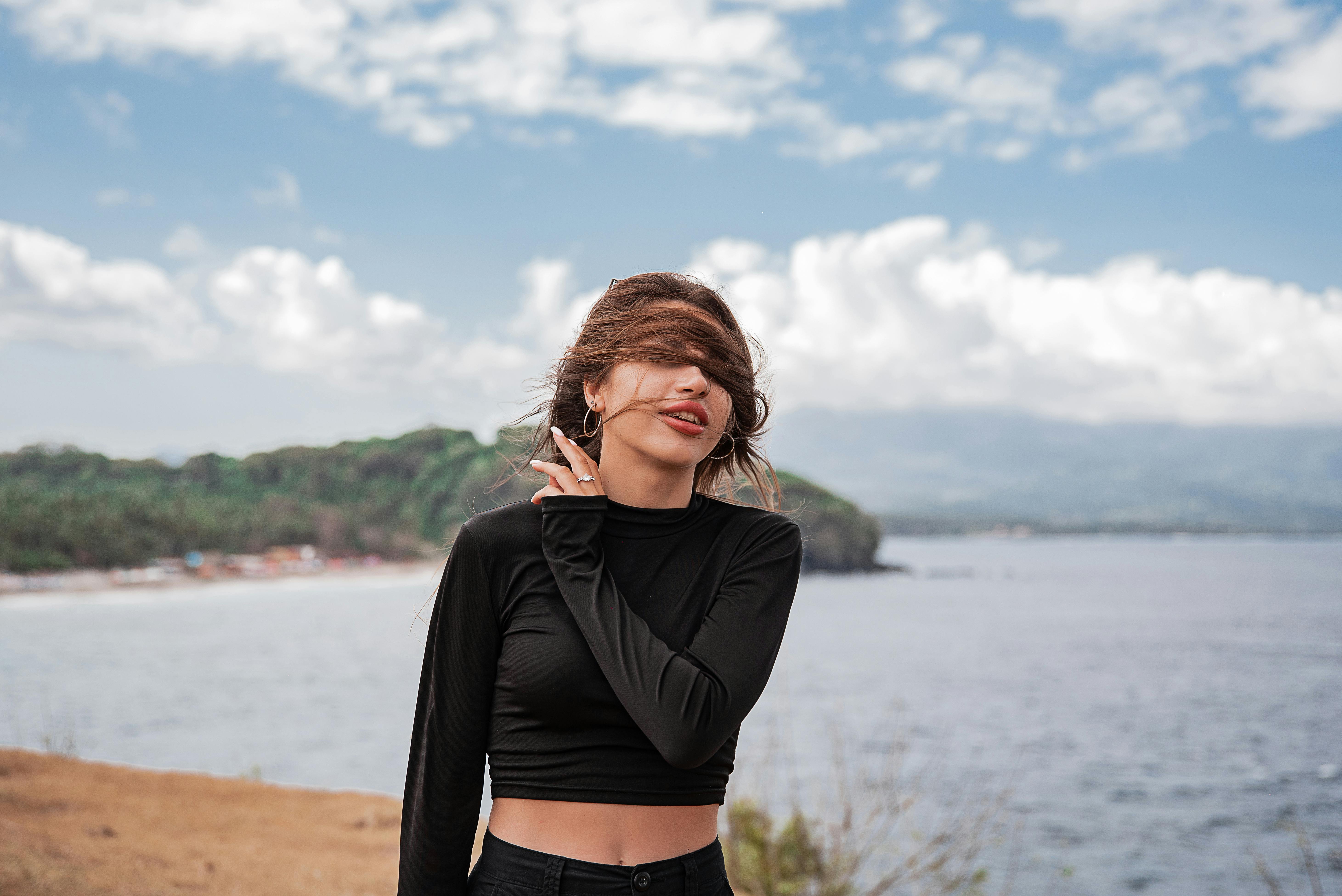 年轻女子在海边享受刮风的日子，表达了自由和快乐