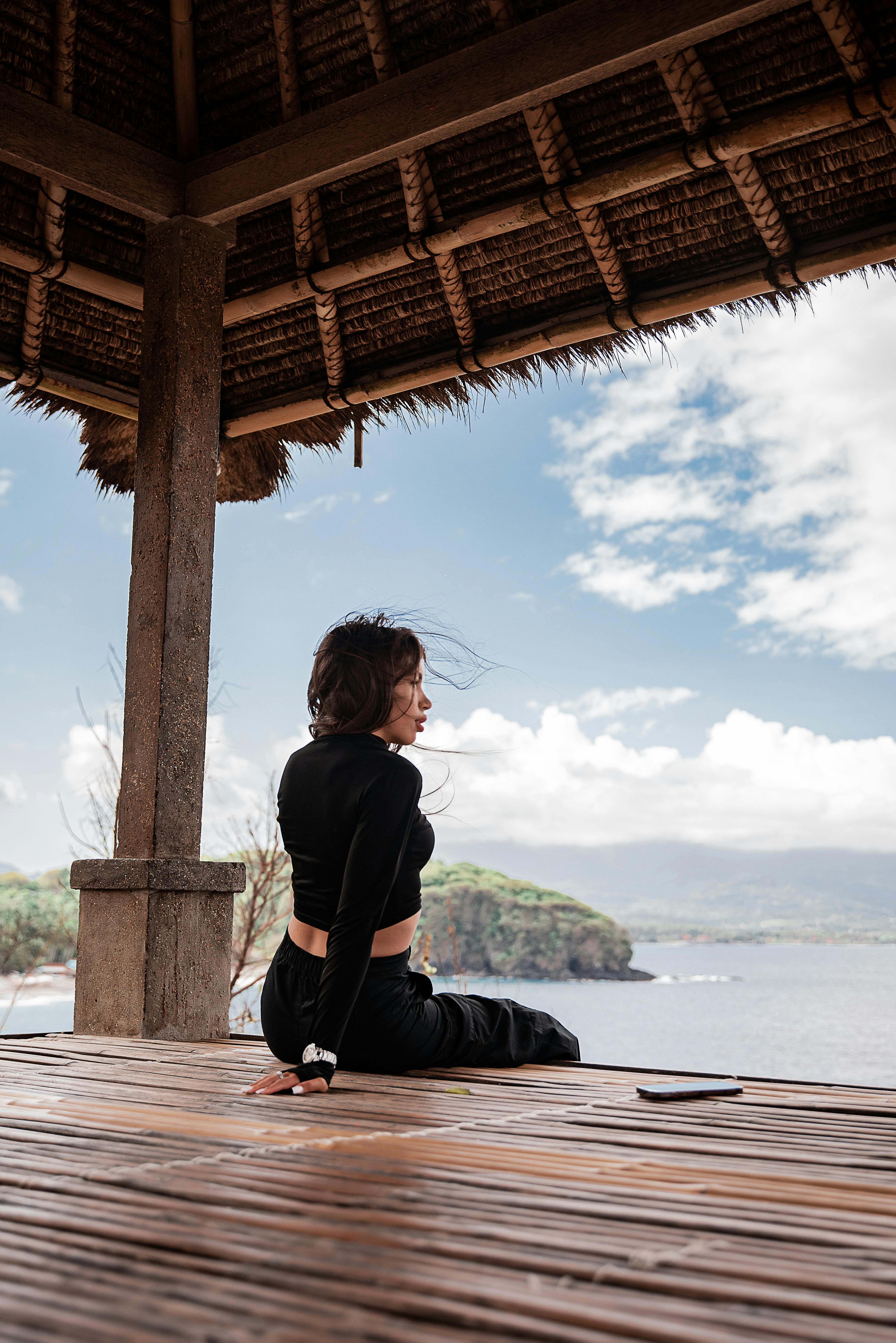 一名女子坐在海滨凉亭里，欣赏宁静的海景