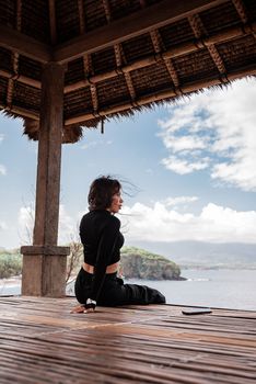 一名女子坐在海滨凉亭里，欣赏宁静的海景