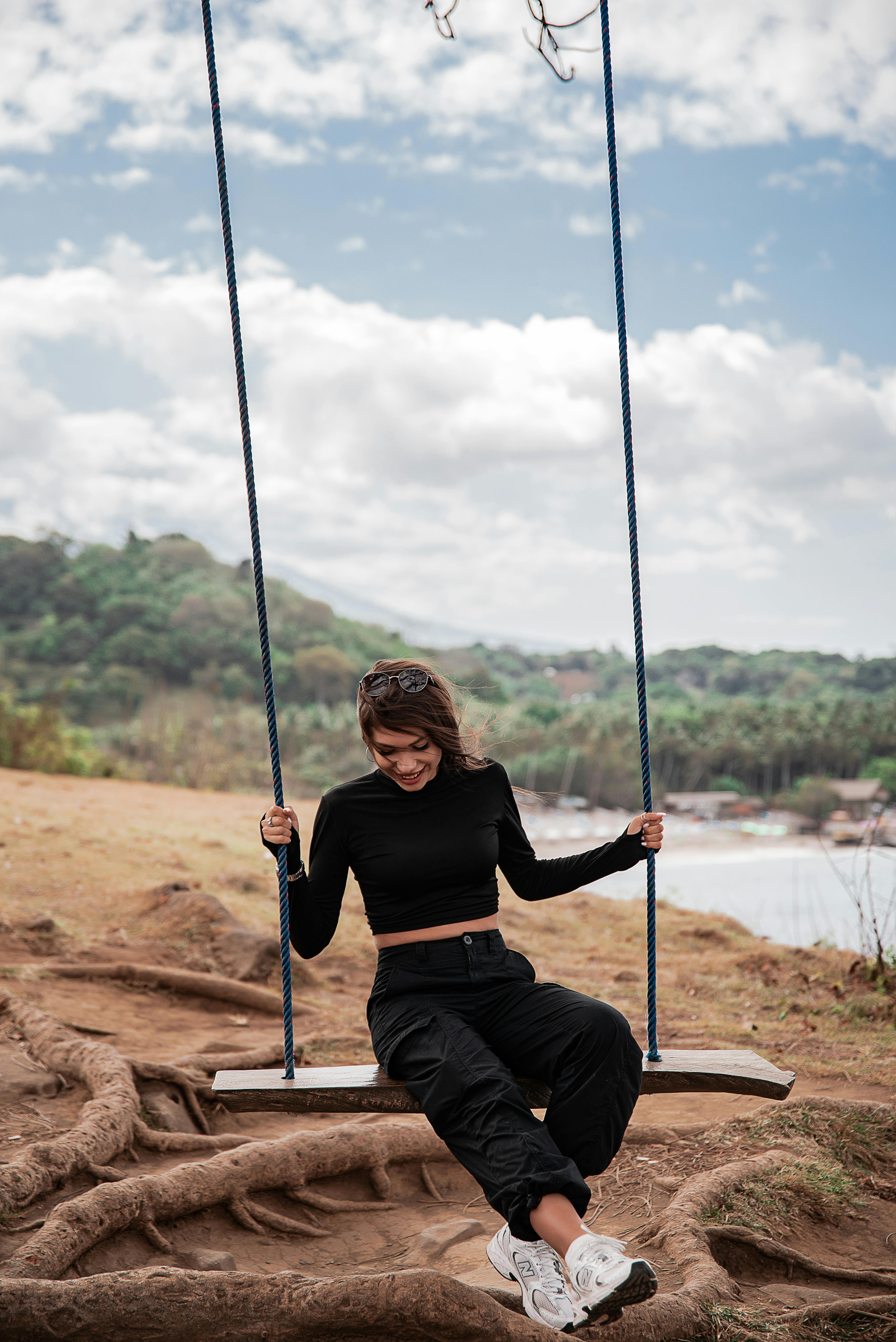 穿着休闲装的年轻女子在风景优美的户外景观中荡来荡去