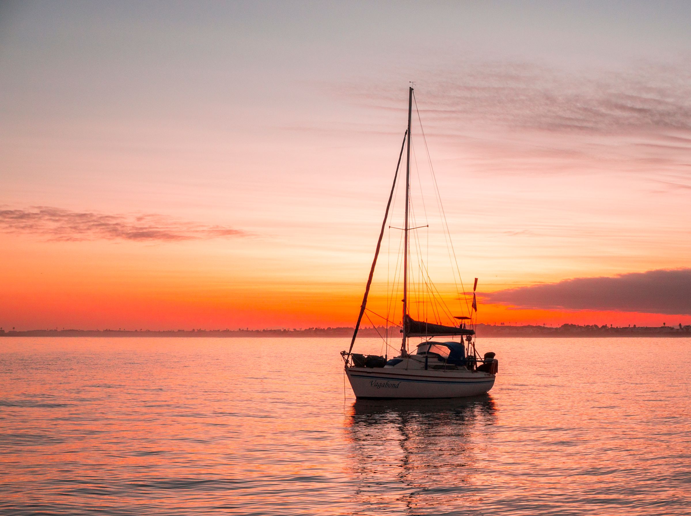 A sailboat at anchor, sails furled, at sunrise in Saint Helena Bay, South Africa