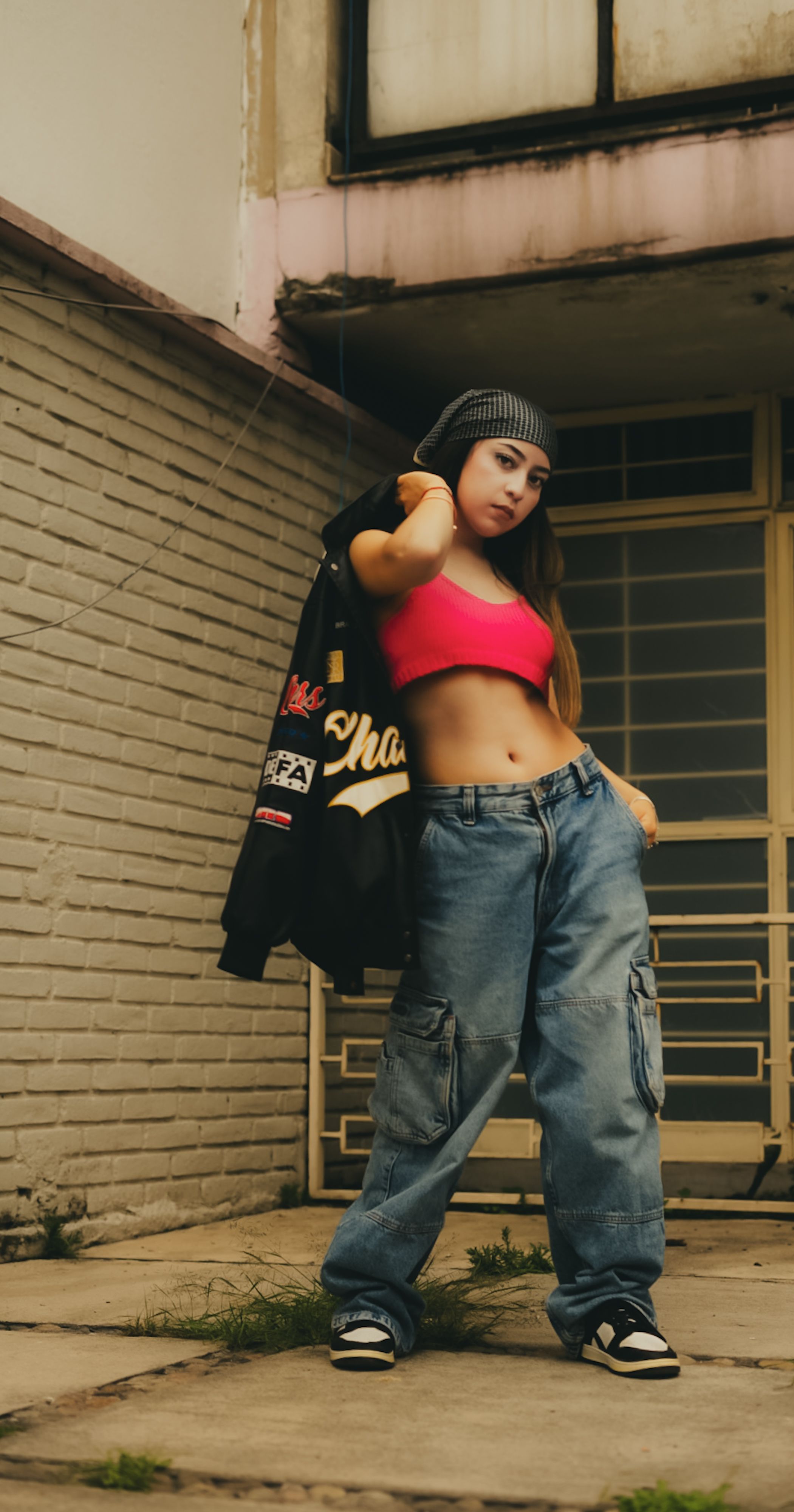 Fashionable young woman posing confidently in urban streetwear outside.