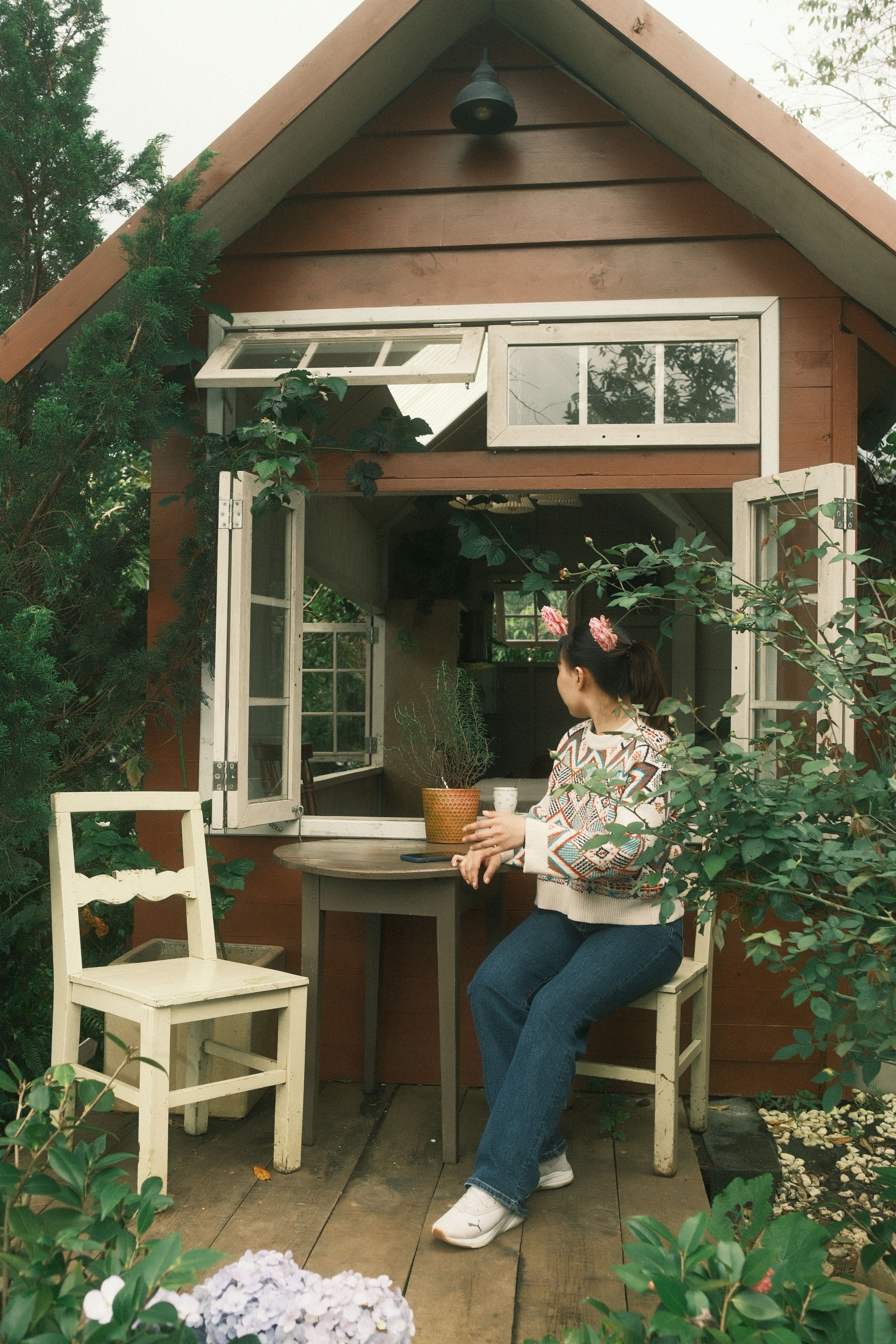 Une femme travaille à la fenêtre ouverte d'un petit studio de jardin