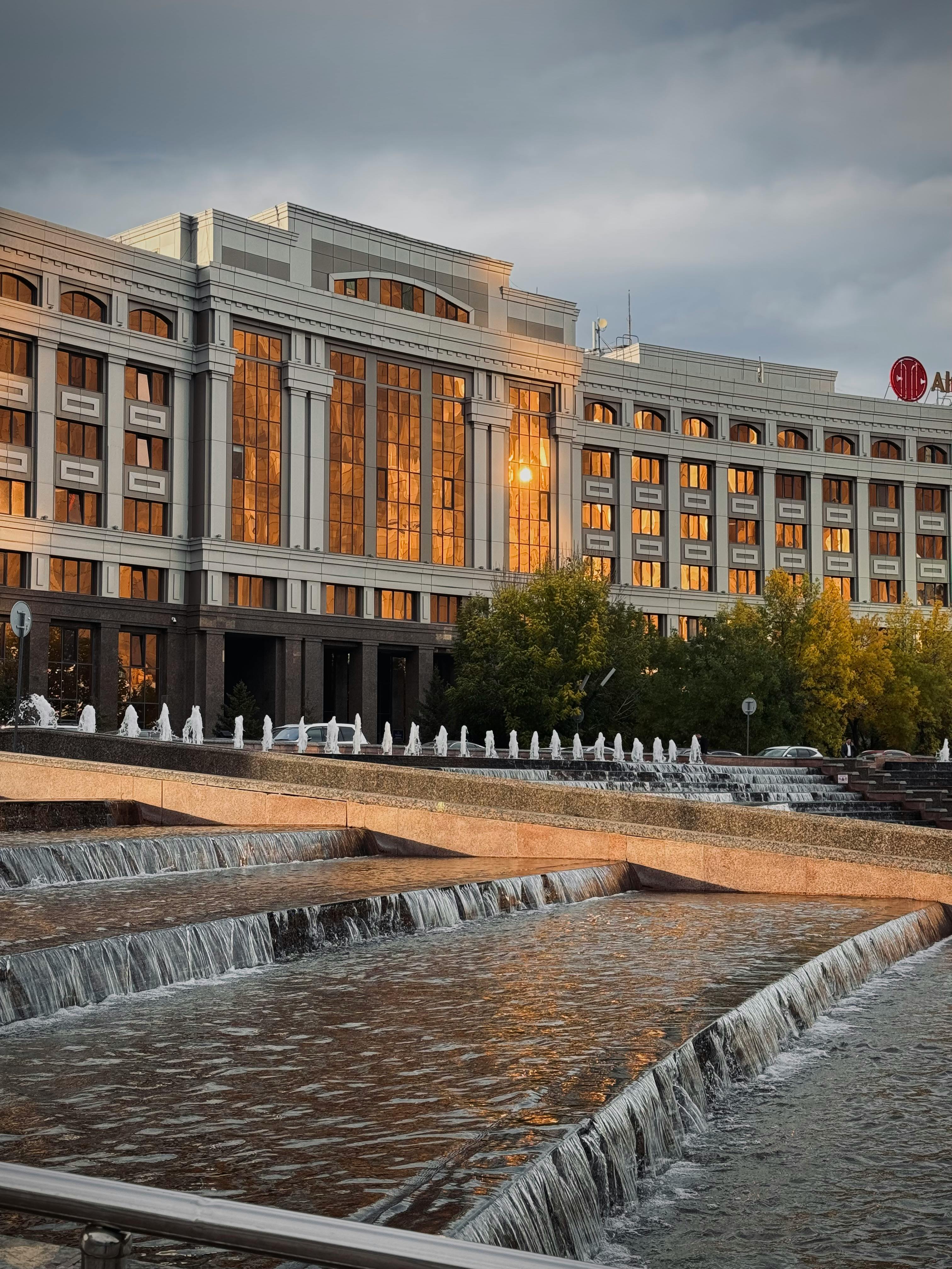 建筑令人印象深刻，夕阳的色彩与层叠的水喷泉在前景