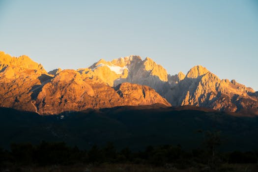 Stunning sunrise over scenic snow-capped mountain peaks with clear skies.