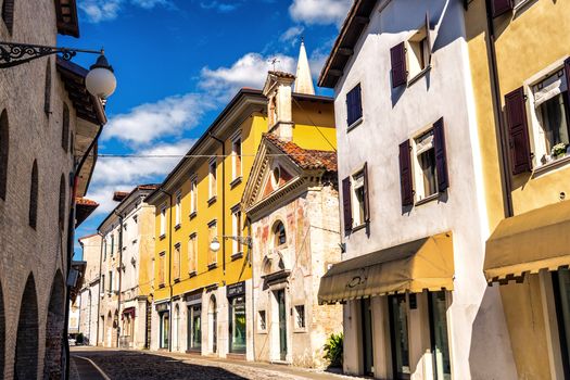 A picturesque view of a charming old street lined with colorful buildings in Europe under a vibrant blue sky.