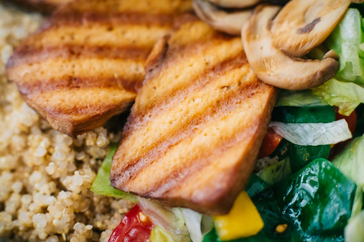 Vegan gut health meal of grilled tofu, quinoa, mushrooms and fresh vegetables in a bowl