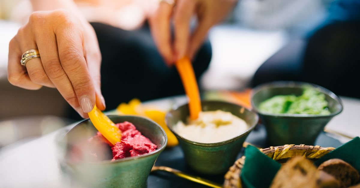 person eating a colorful snack bowl at a desk with natural lighting