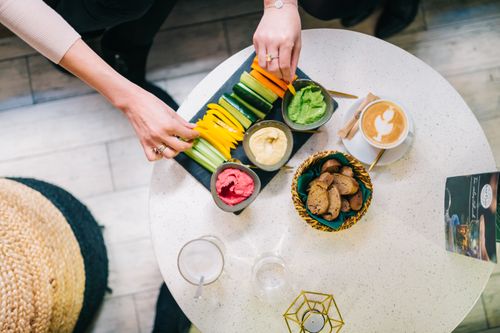 Free Top view of a healthy snack platter with colorful vegetables, dips, and coffee on a table. Stock Photo