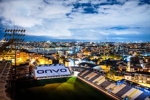 Photo by Sami TÜRK Aerial view of Istanbul's vibrant skyline at night with a focus on a well-lit stadium.