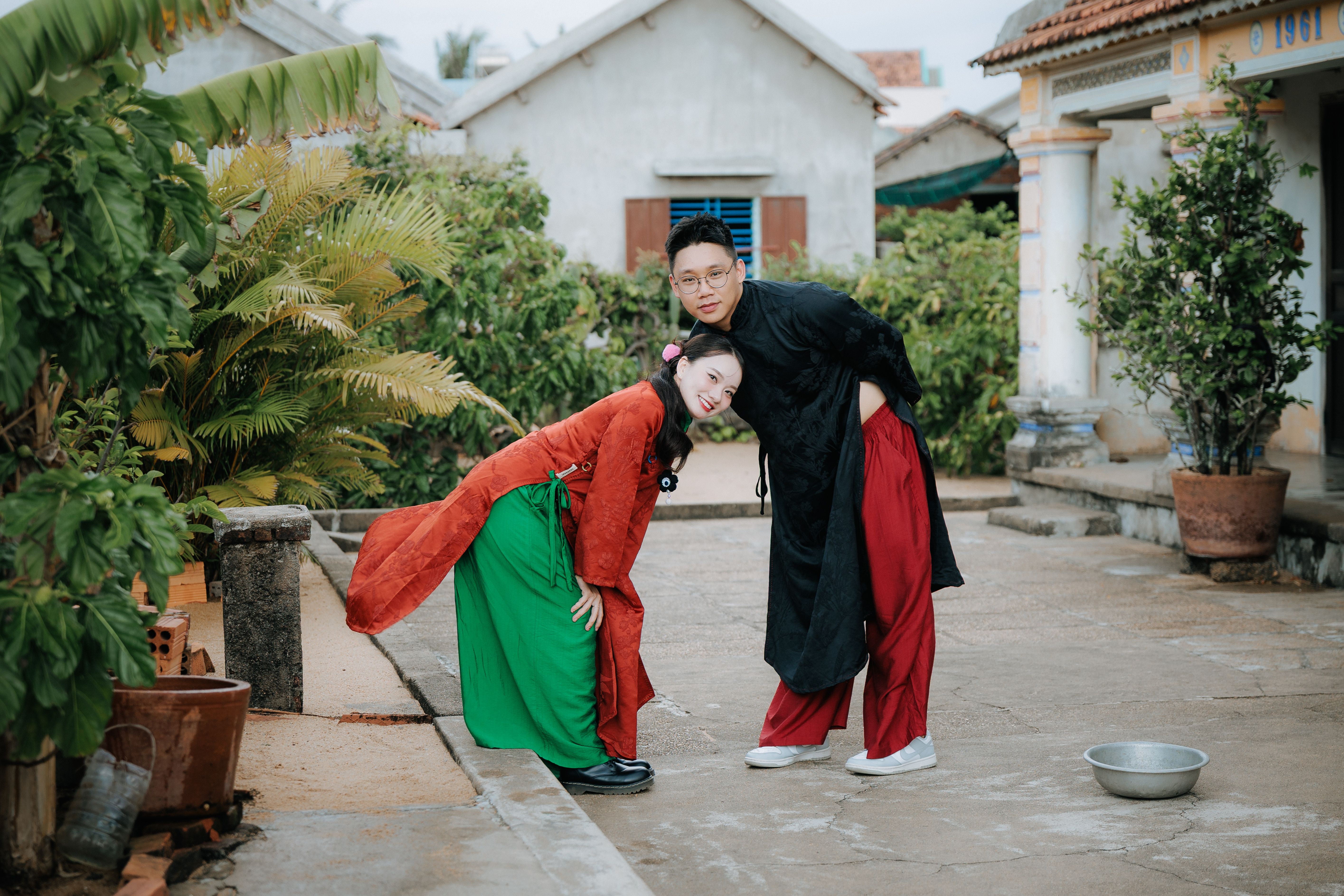 Vietnamese village festival courtyard with traditional rooster keepers, red banners, and curious families