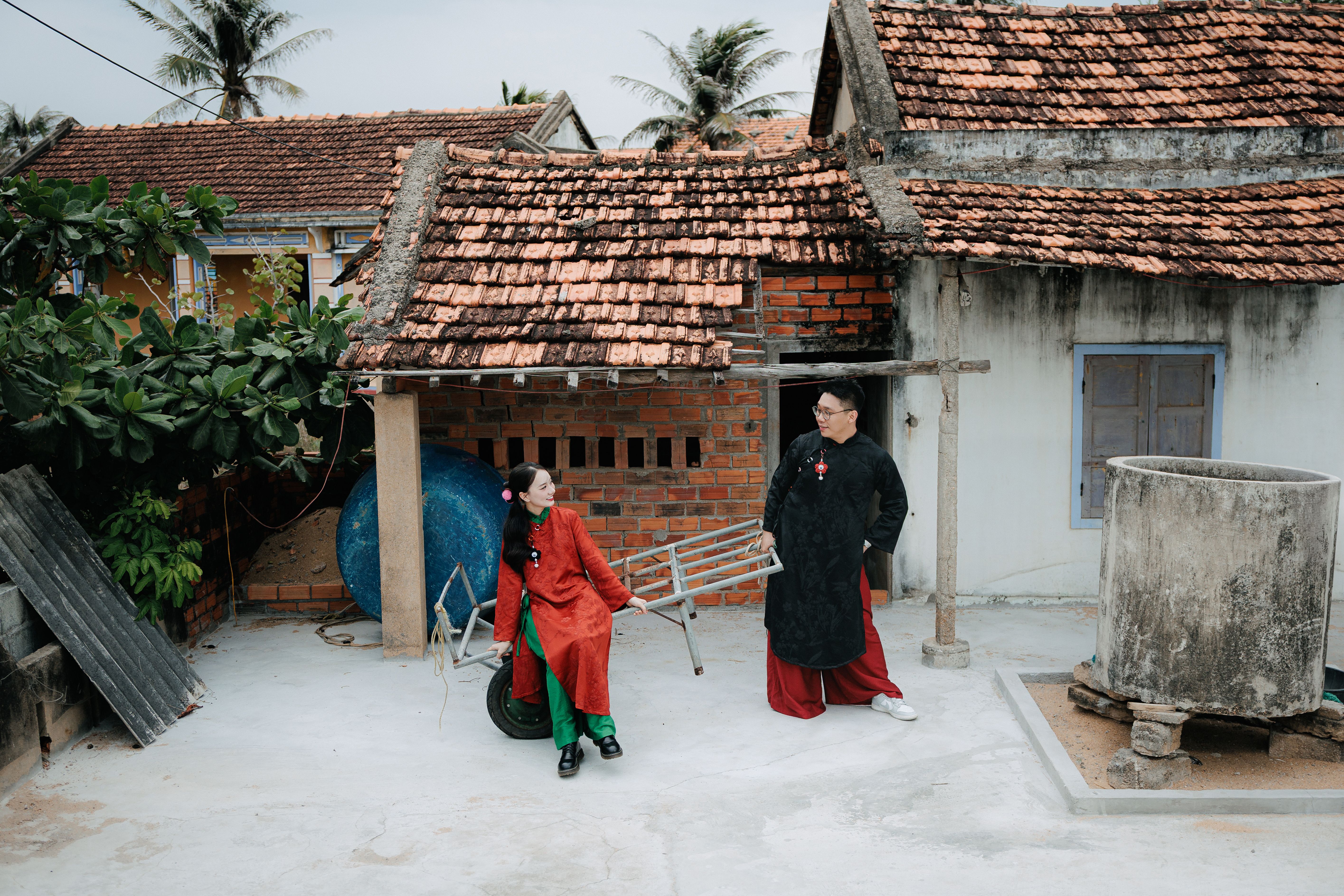 A vibrant scene of locals in traditional attire in a Vietnamese courtyard setting.