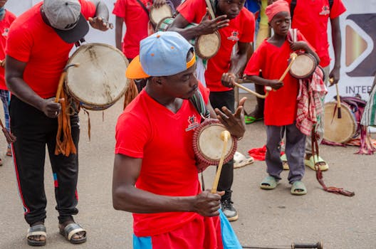 Young musicians performing with traditional drums in a lively outdoor street scene in Togo.
