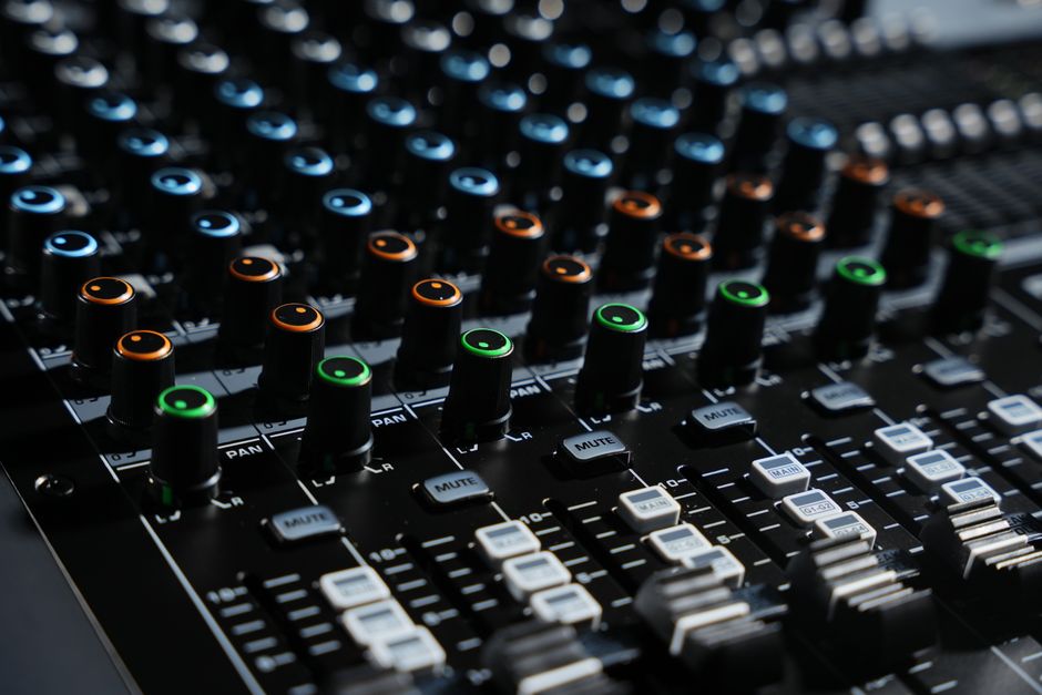 Detailed view of an audio mixing console with colorful lights in a professional studio setting.