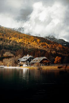 Picturesque autumn landscape with a cabin by a lake in Austria, surrounded by vibrant fall foliage.