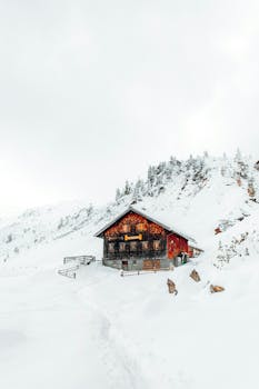 Quaint wooden cabin nestled in a snowy mountain scene in Austria.