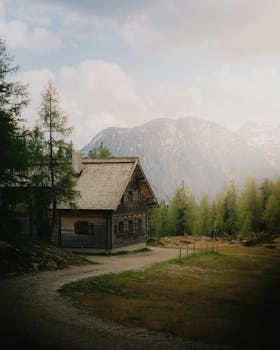 Charming wooden cabin in Austrian Alps, surrounded by lush greenery and majestic mountains.