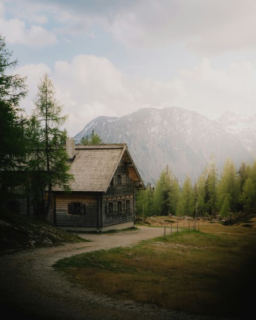 Free Charming wooden cabin in Austrian Alps, surrounded by lush greenery and majestic mountains. Stock Photo