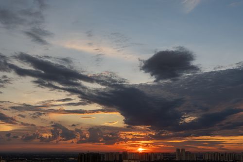 Free Stunning sunset skyline with dramatic clouds casting shadows over urban buildings. Stock Photo