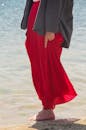 穿着红色裙子的女人赤脚站在海边，捕捉到宁静与自由