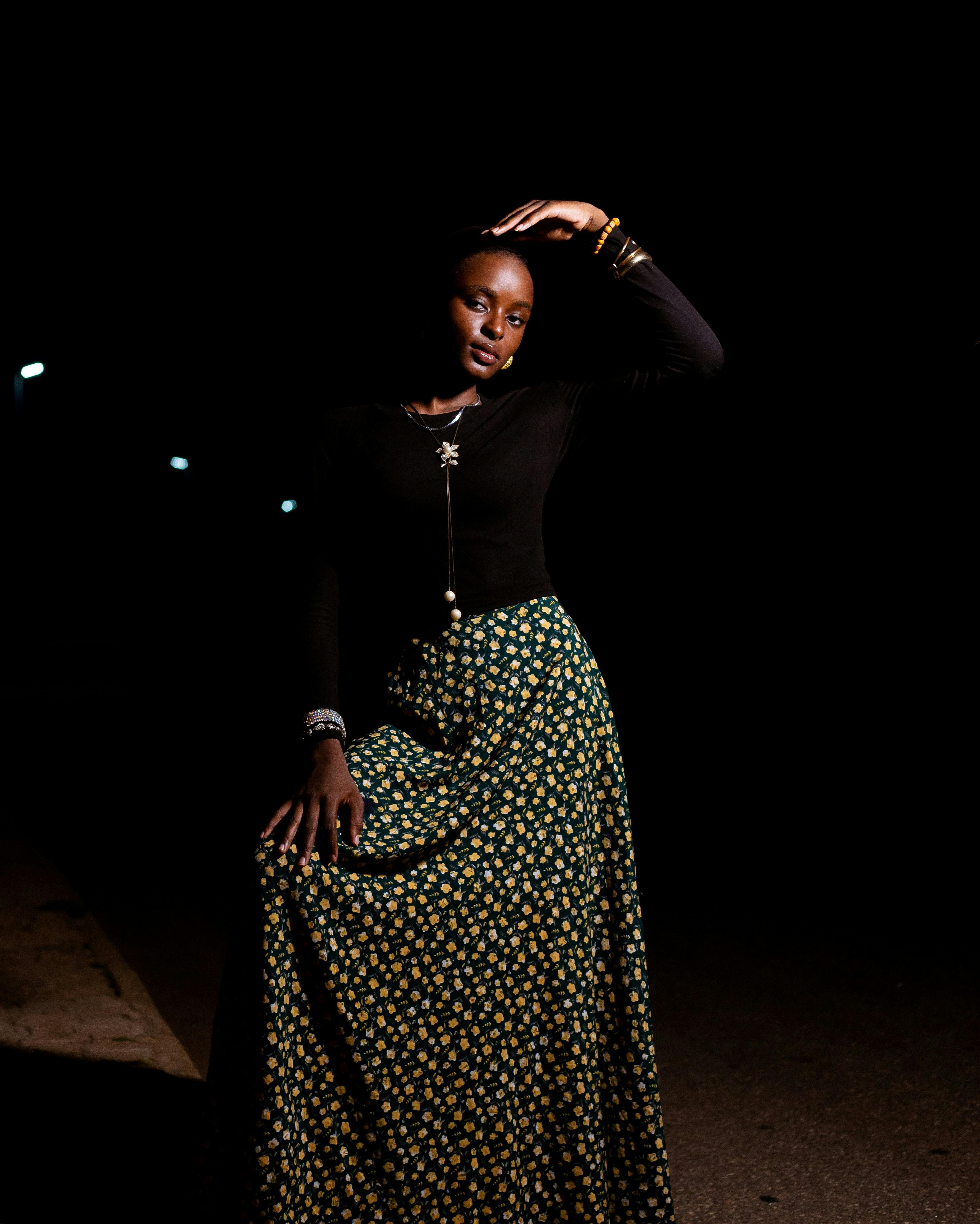时尚的女人在夜晚的灯光下自信地摆姿势，用花裙子展示优雅的时尚感