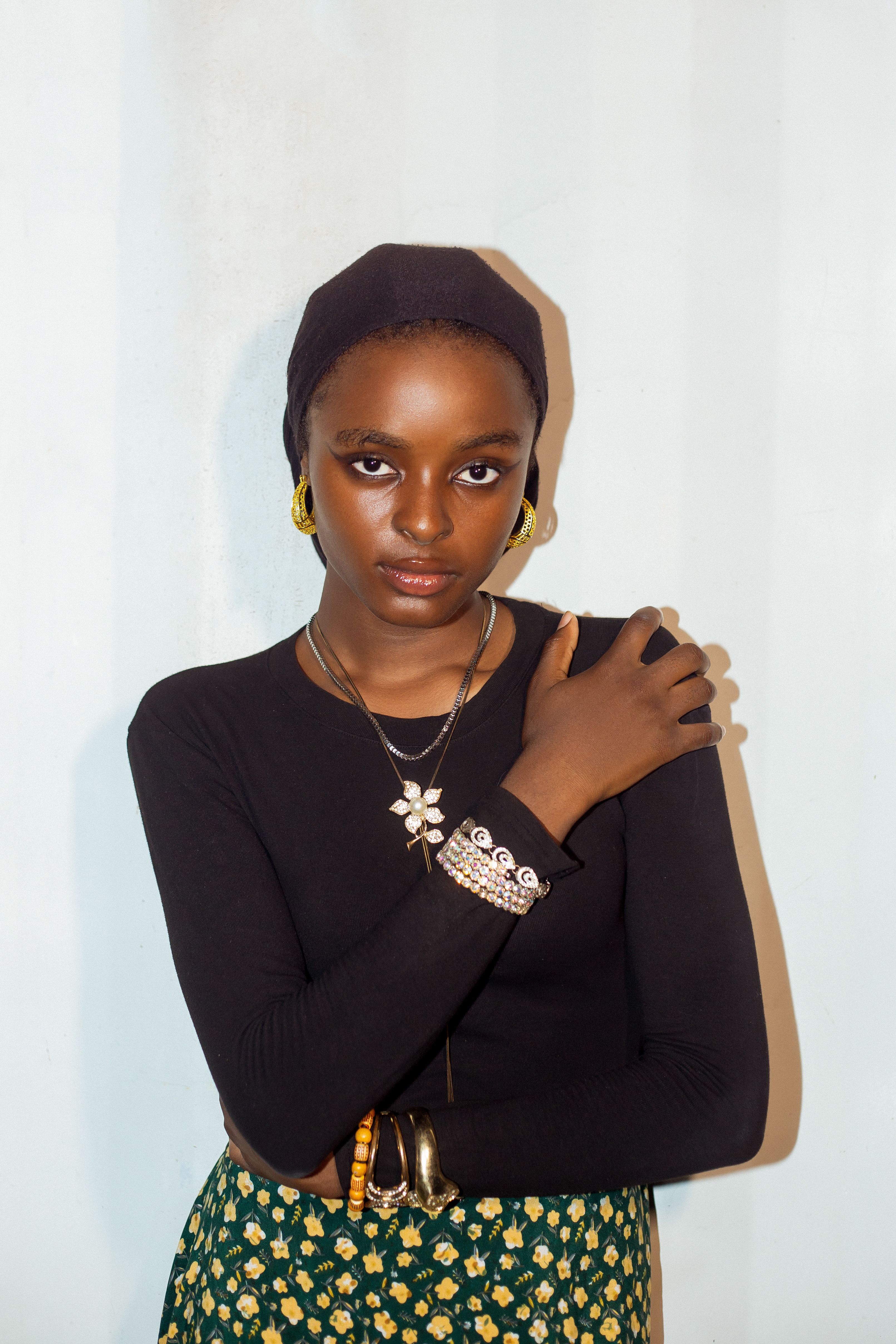 Portrait of a young woman in a stylish black top and patterned skirt, exuding confidence.