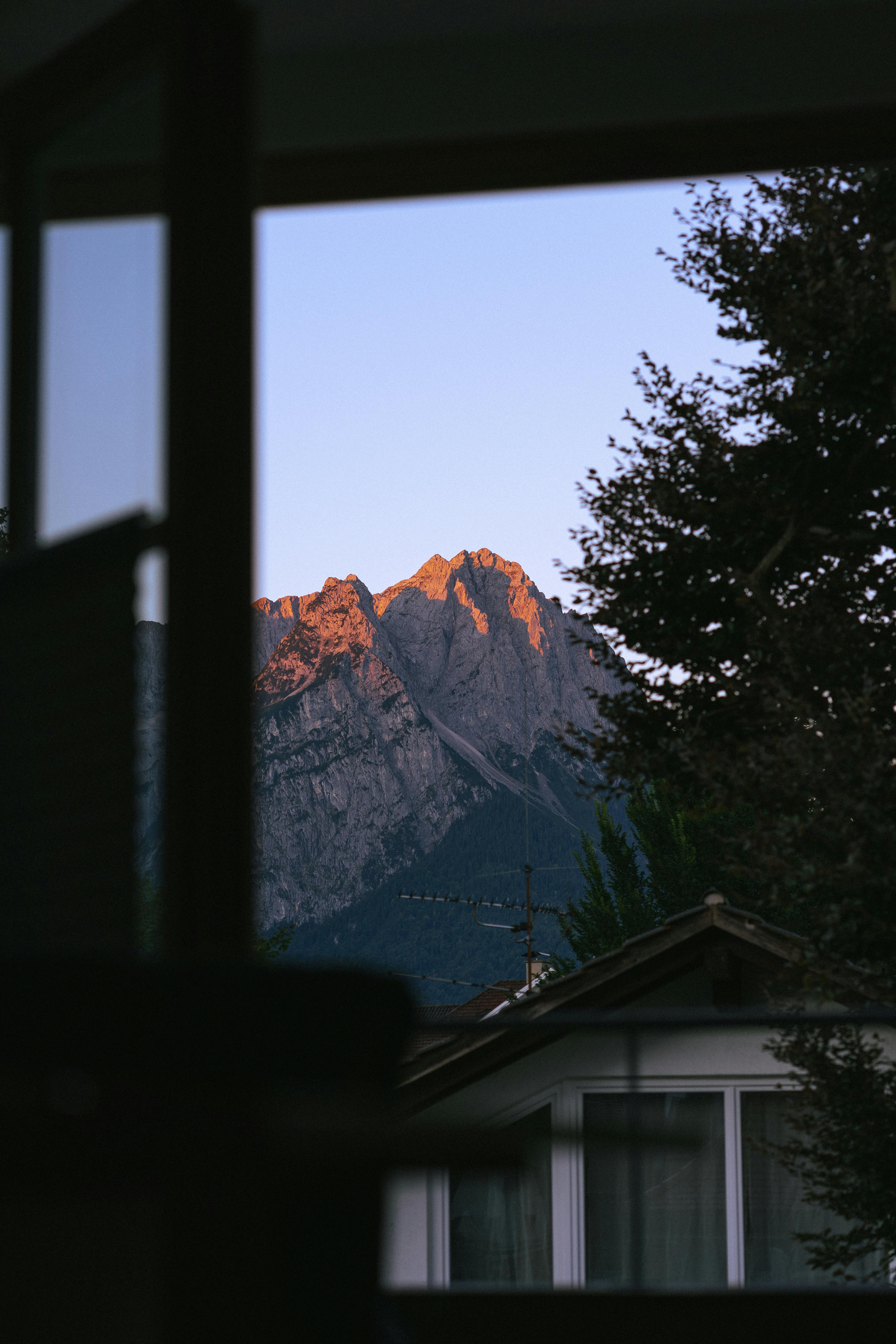 在日落时分，通过房屋的窗户欣赏到那如画般美丽的山脉景色