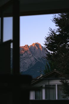 在日落时分，通过房屋的窗户欣赏到那如画般美丽的山脉景色