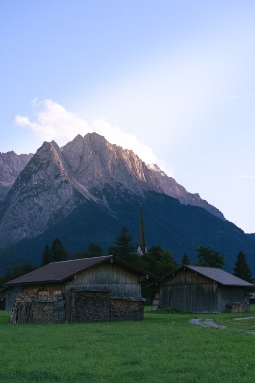 Free Charming farmhouses with dramatic mountain scenery during twilight. Stock Photo