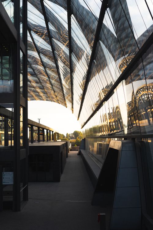Free A captivating view of architectural reflections on a glass bridge at sunset. Stock Photo